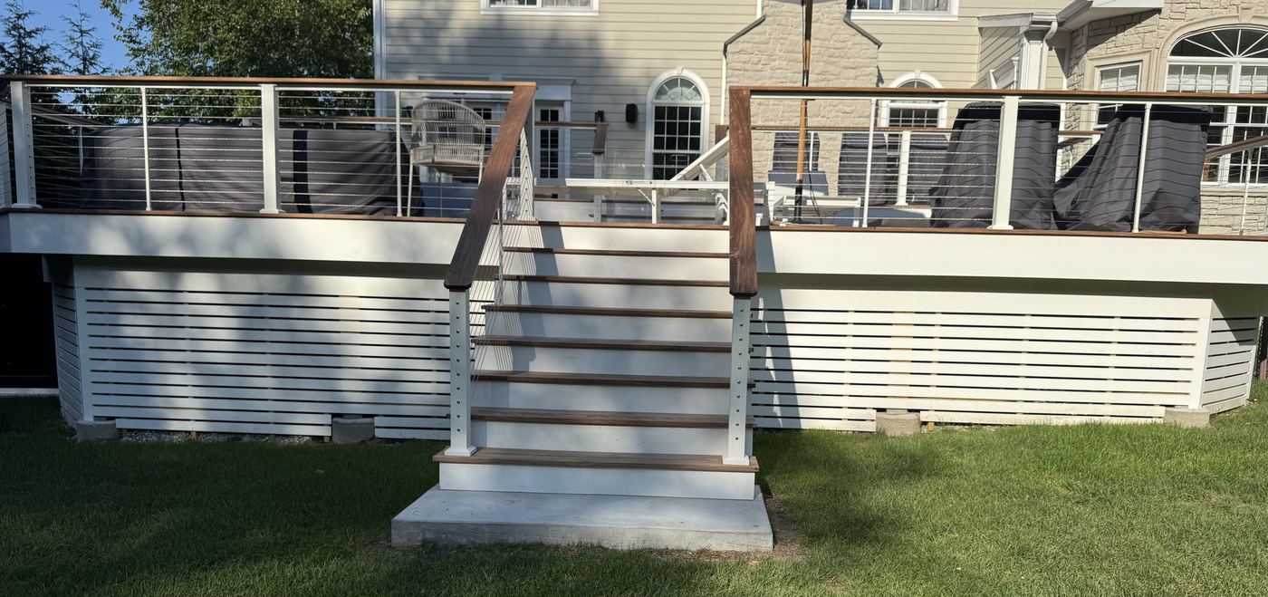 Deck stairway with bare foundation and open lawn before planting