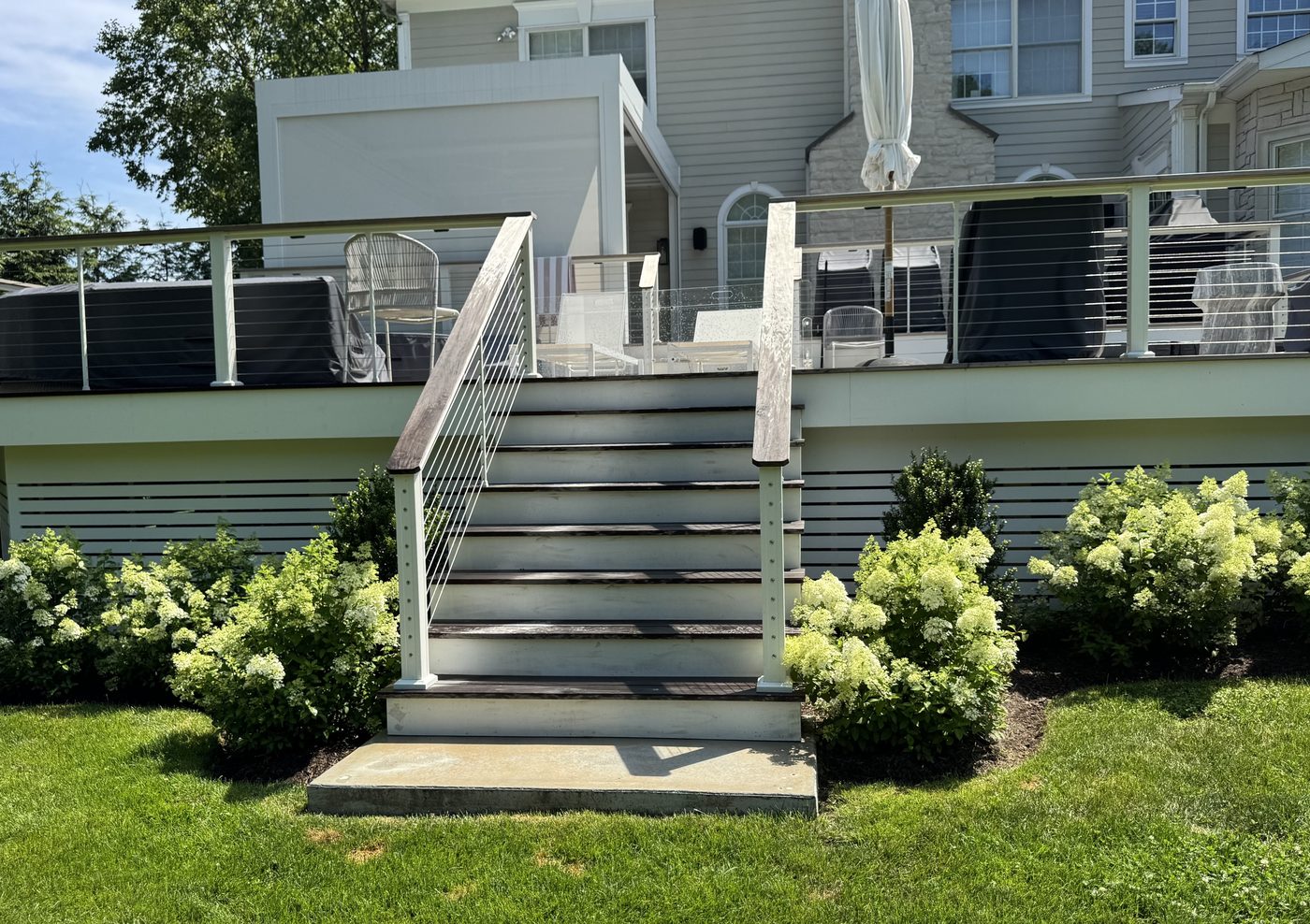 Same deck stairway with hydrangea shrubs planted along the foundation